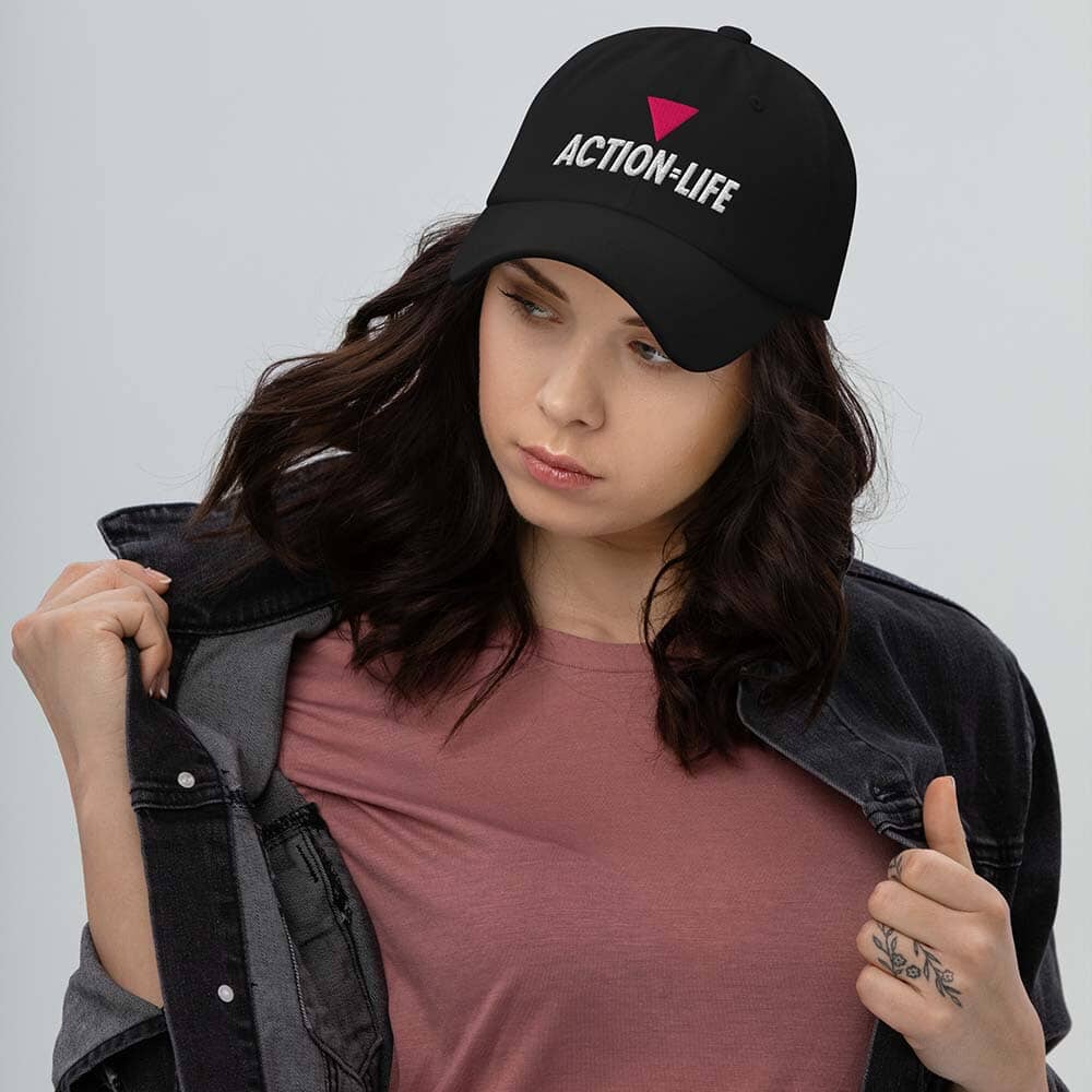 Woman wearing a black cap with action = life logo on a gray background