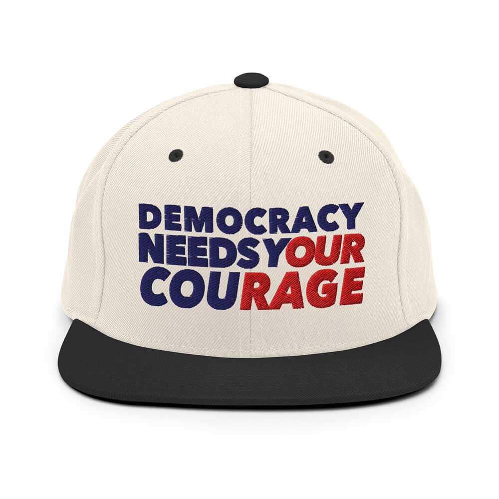Cap with 'Democracy Needs Your Courage' text on a white background