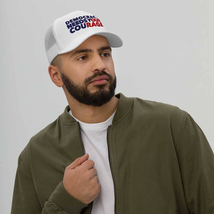 Man wearing a white cap and green jacket against a plain background