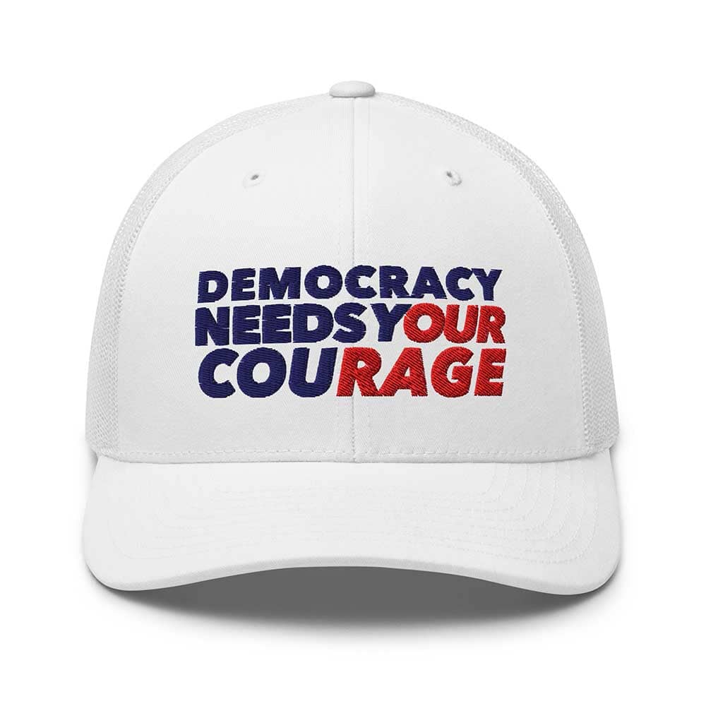 White cap with 'Democracy Needs Your Courage' text in blue and red on a white background