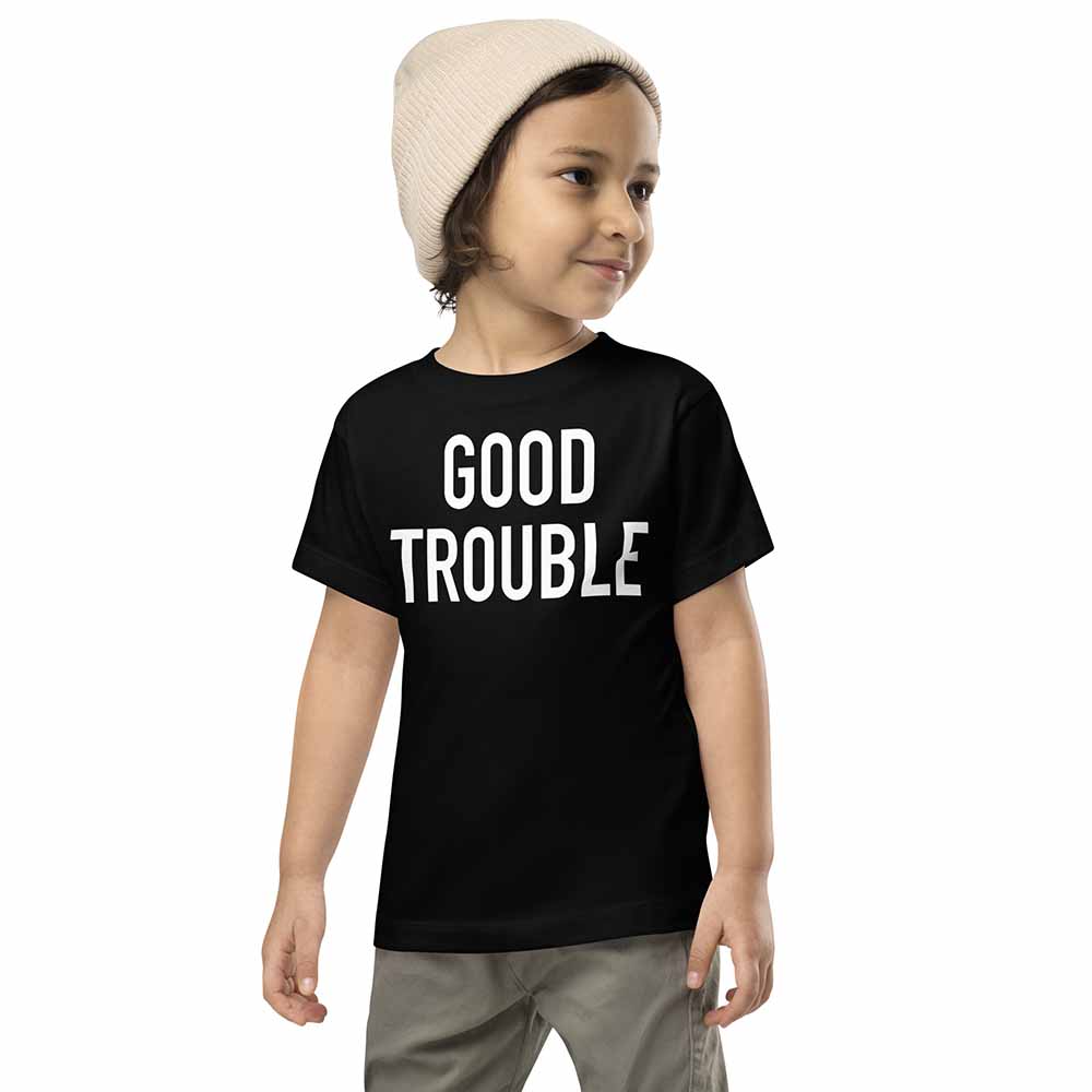 Child wearing a black t-shirt with 'GOOD TROUBLE' text on a white background