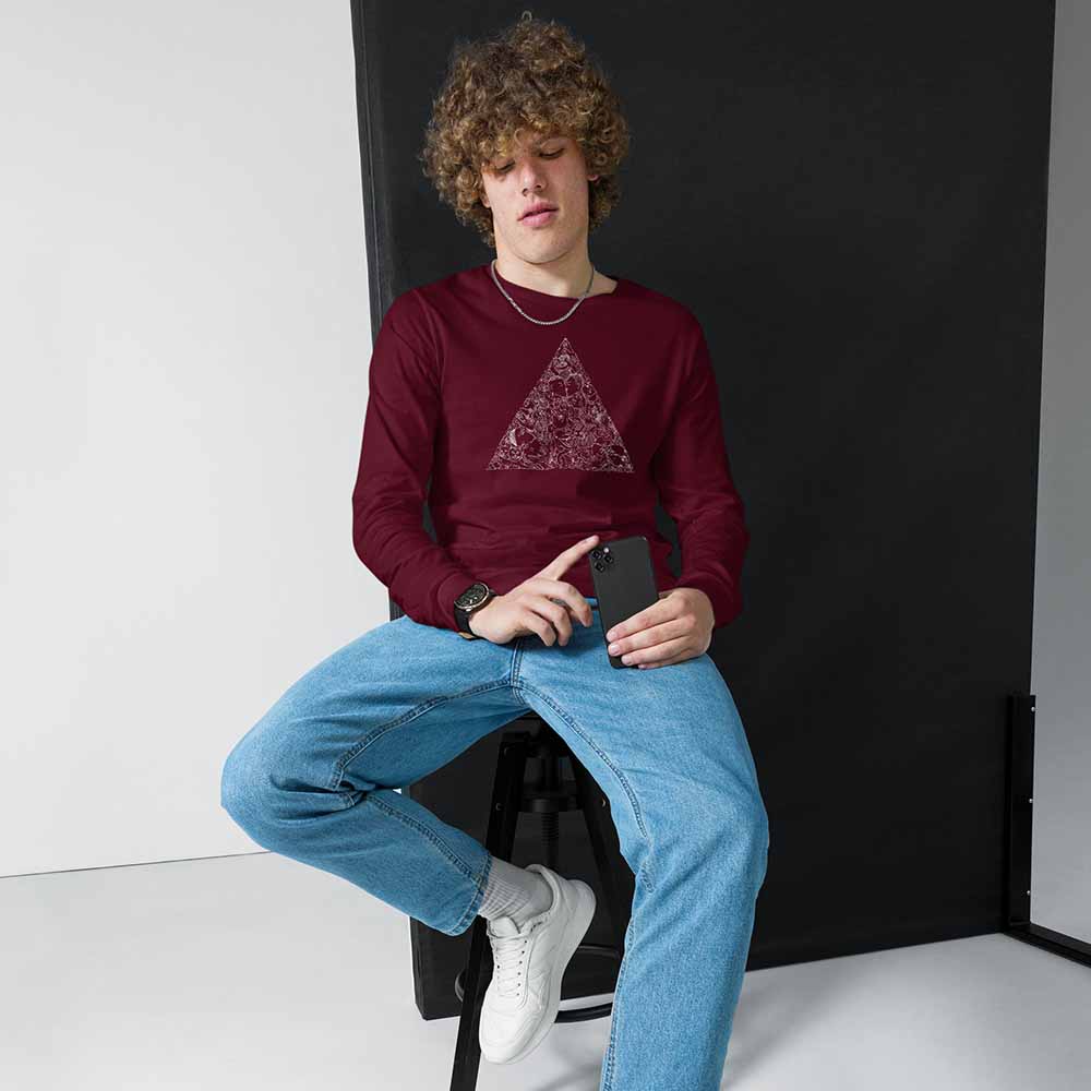 Person wearing a maroon sweatshirt with a geometric design and blue jeans, sitting on a black stool.