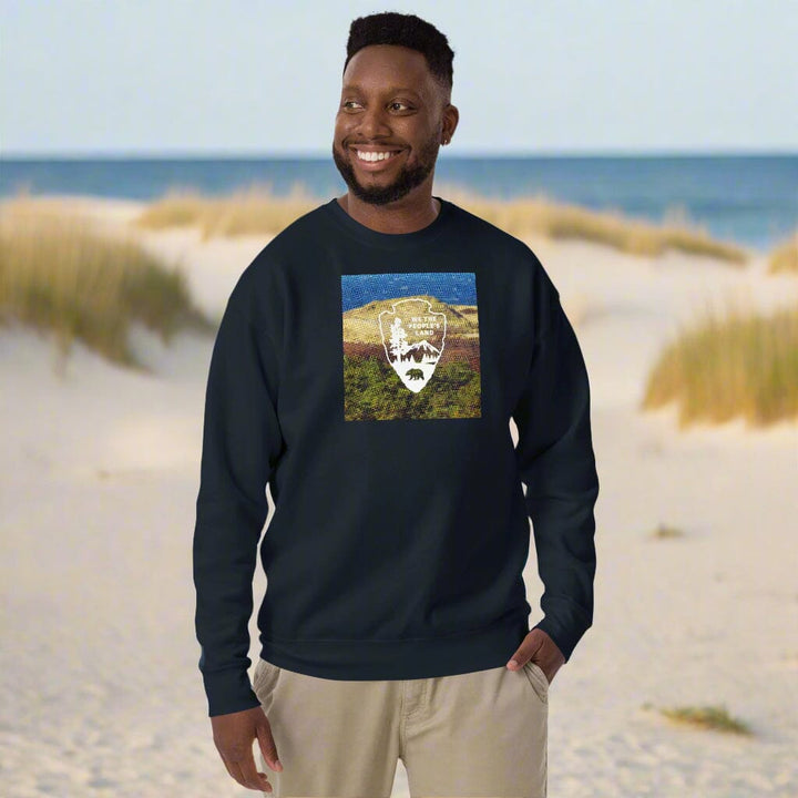 Man wearing a navy blue sweatshirt with a graphic design in sand dunes 