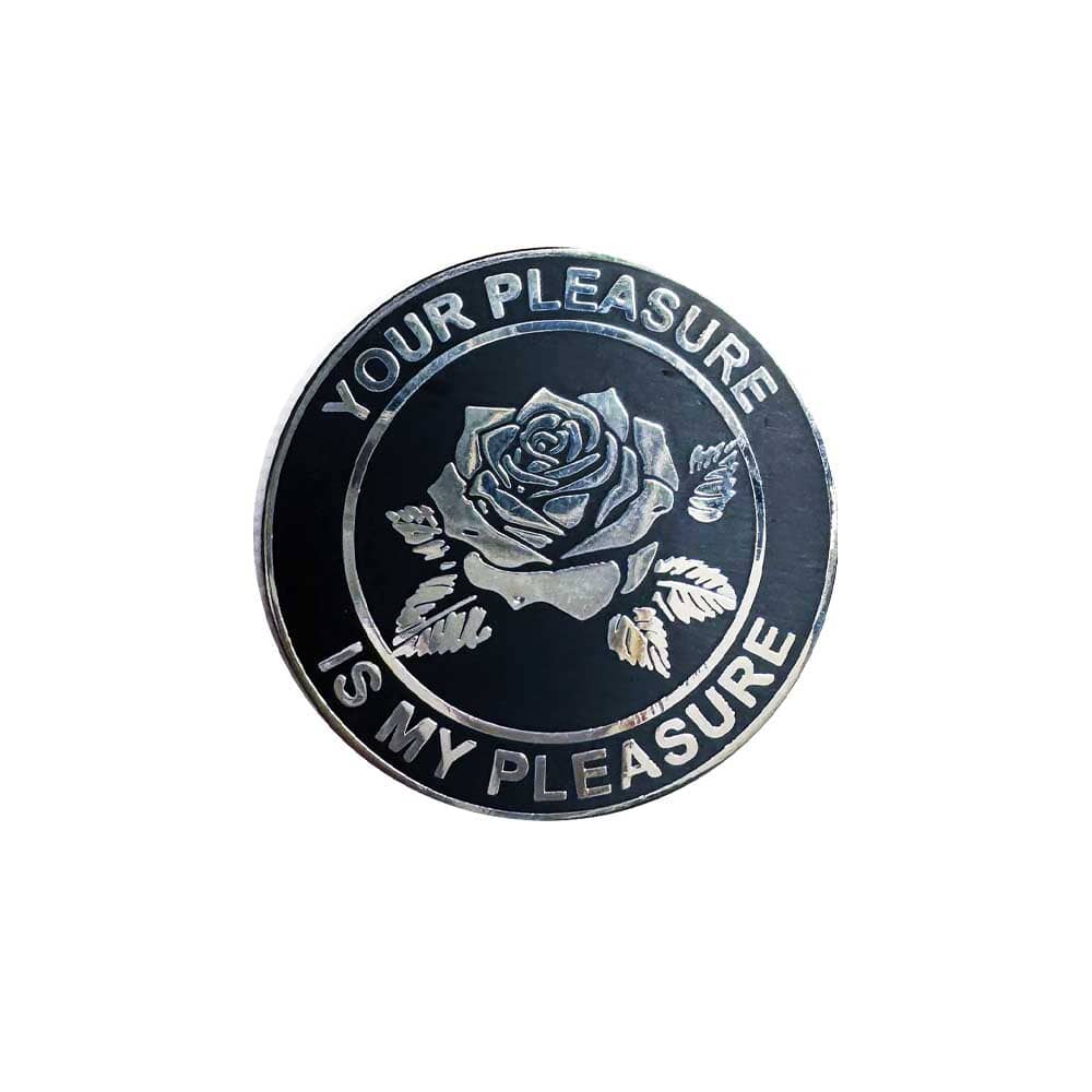 Round metal badge with rose design and text 'Your Pleasure is My Pleasure' on a white background