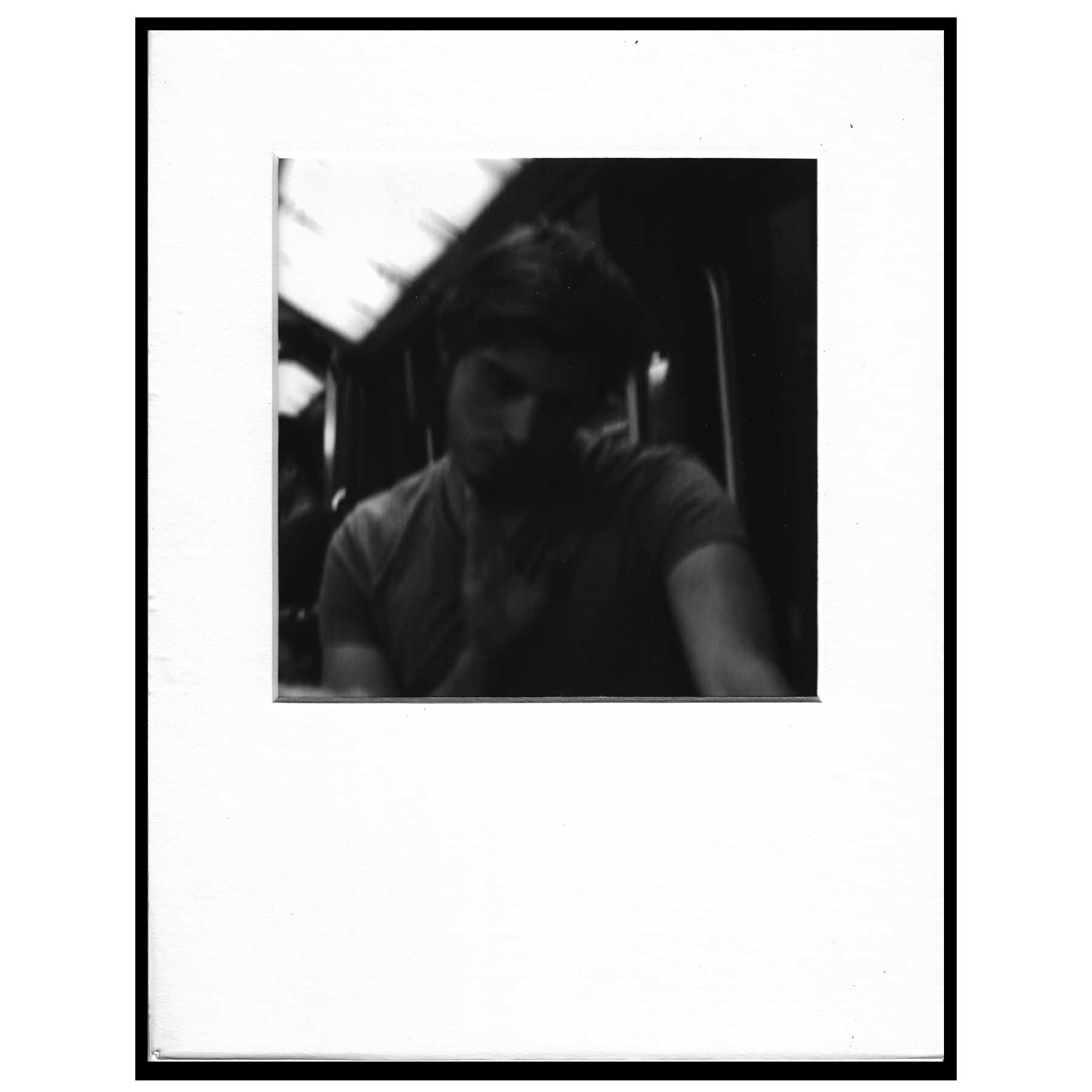black and white photograph of man on subway in grey t-shirt
